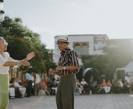 Elderly couple dancing in sunlit León de los Aldama plaza, showcasing joy and community spirit.
