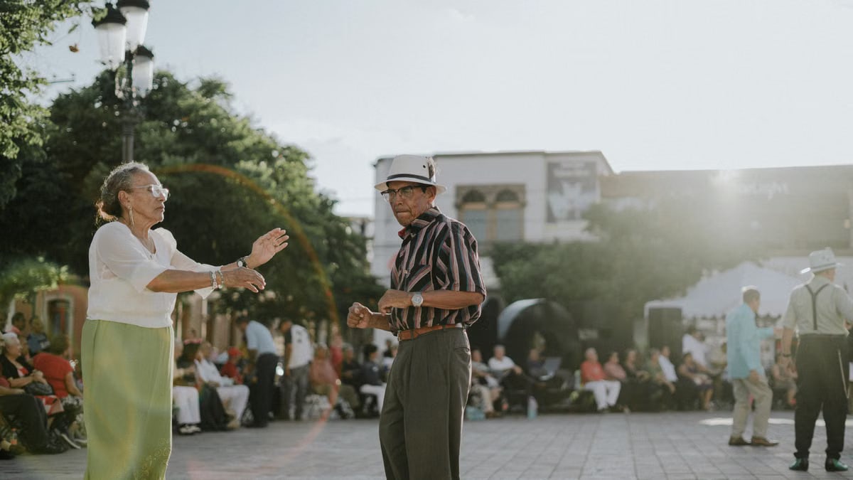 Elderly couple dancing in sunlit León de los Aldama plaza, showcasing joy and community spirit.